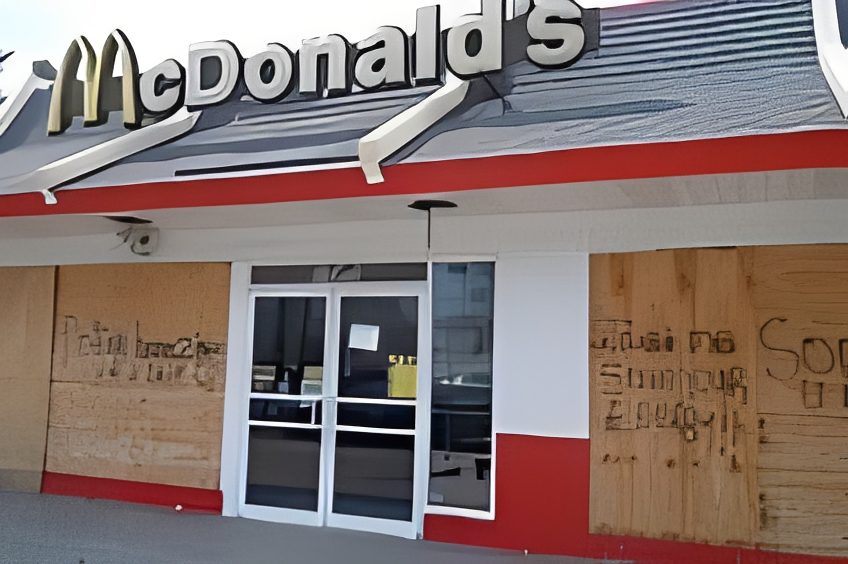Boarded-up McDonald's storefront with graffiti.