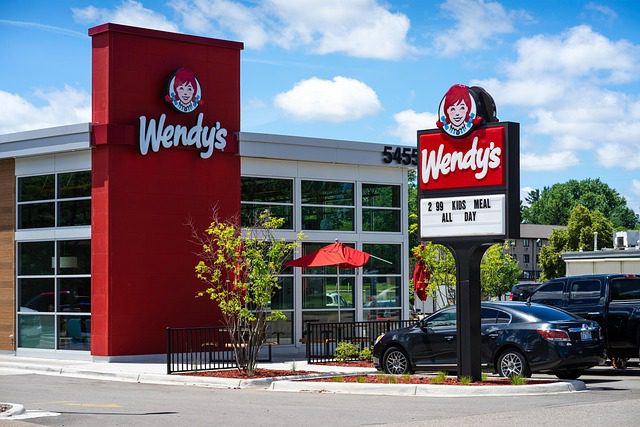 Wendy's fast food restaurant with outdoor seating and a clear blue sky.